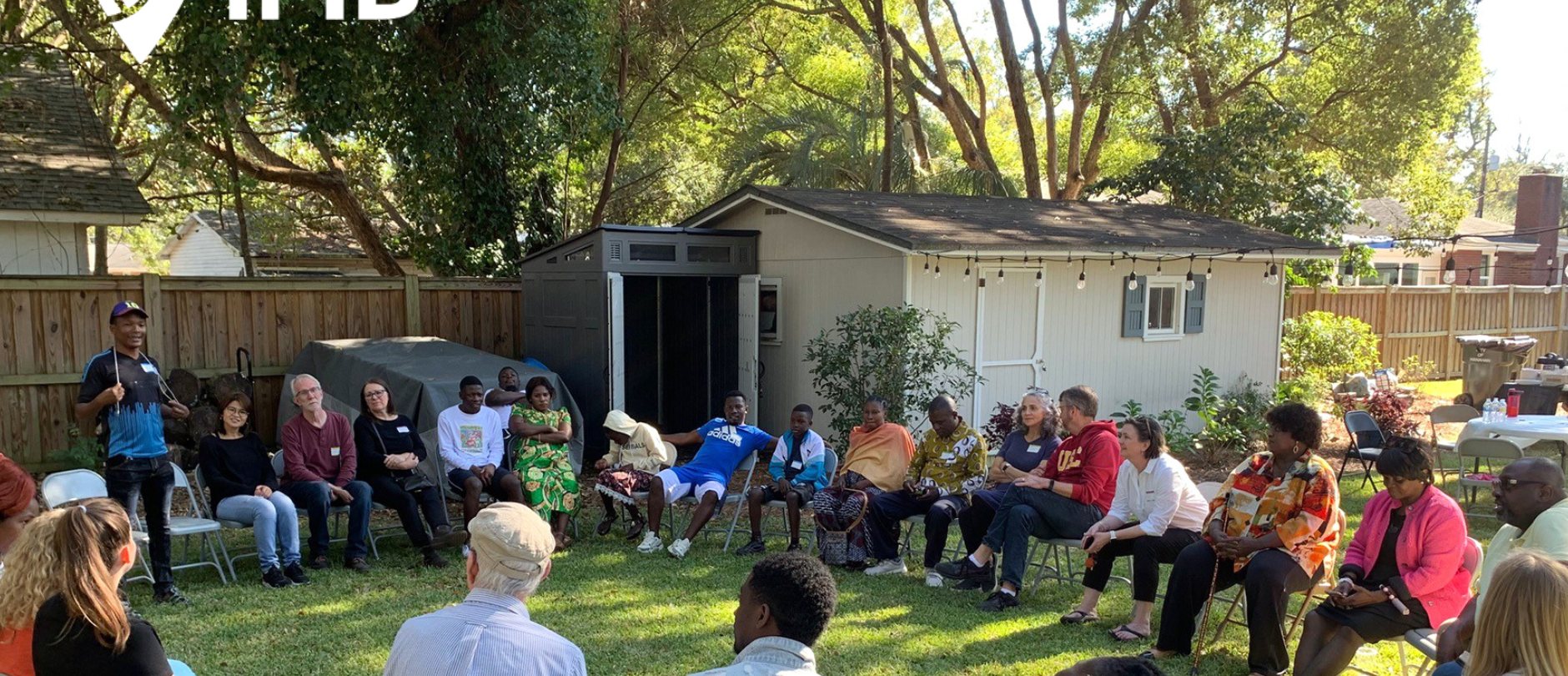 A microcommunity gathered in a circle of chairs in a backyard