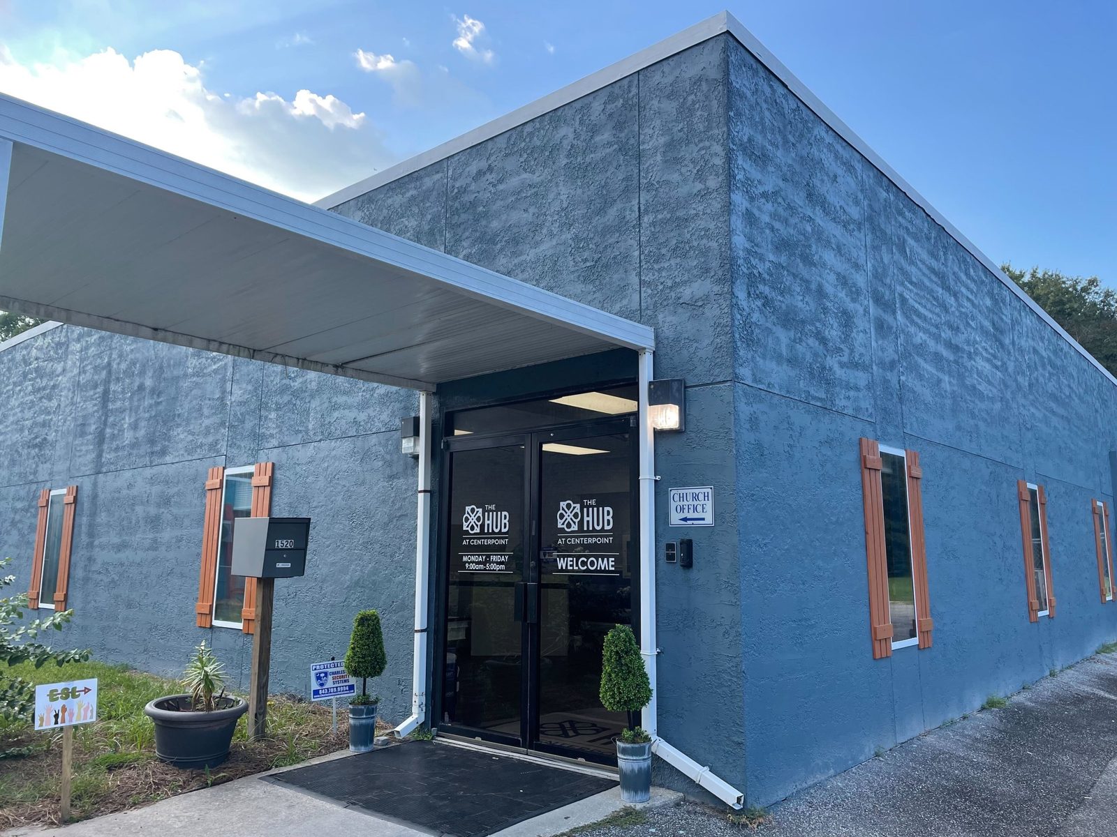 The exterior of a Hub campus building with a bright blue door