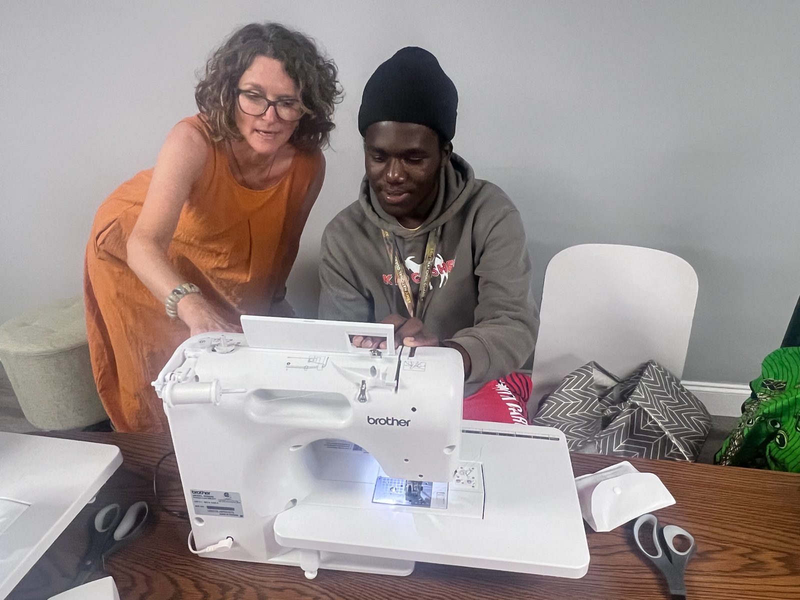 A volunteer helping a man at a sewing machine