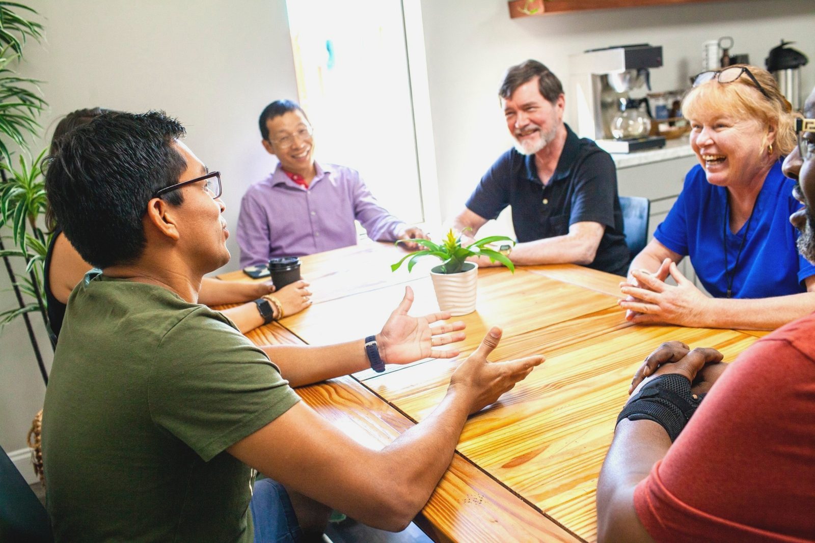 Four people laughing around a table at the Hub